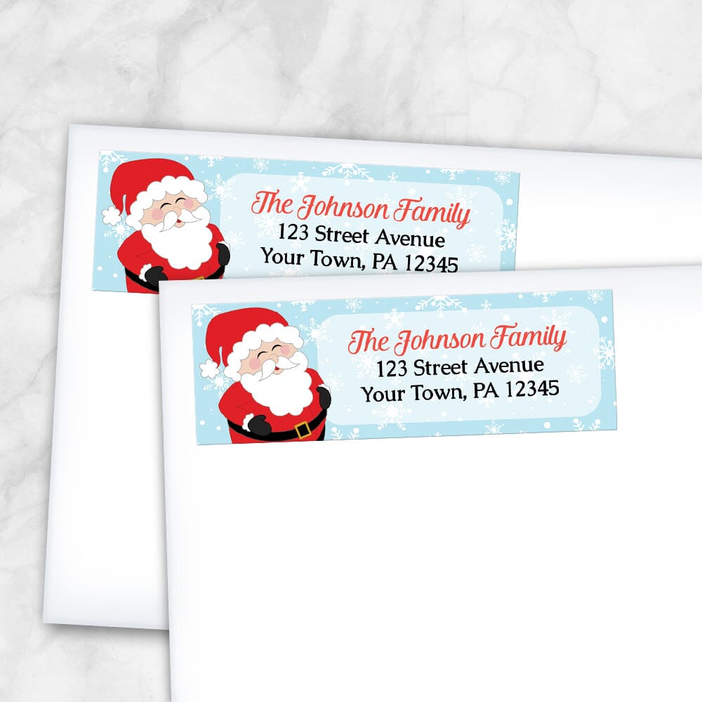 Cheerful Santa Address Labels at Artistically Invited. Cute return address labels illustrated with a cheerful and jolly Santa Claus, holding his belly and laughing, on the left side of the labels over a light blue winter background with white snowflakes. Your personalized return address is custom printed in red and black to the right of the cute Santa Claus over a lighter rectangular area of the light blue background. Example shows the labels on envelopes.