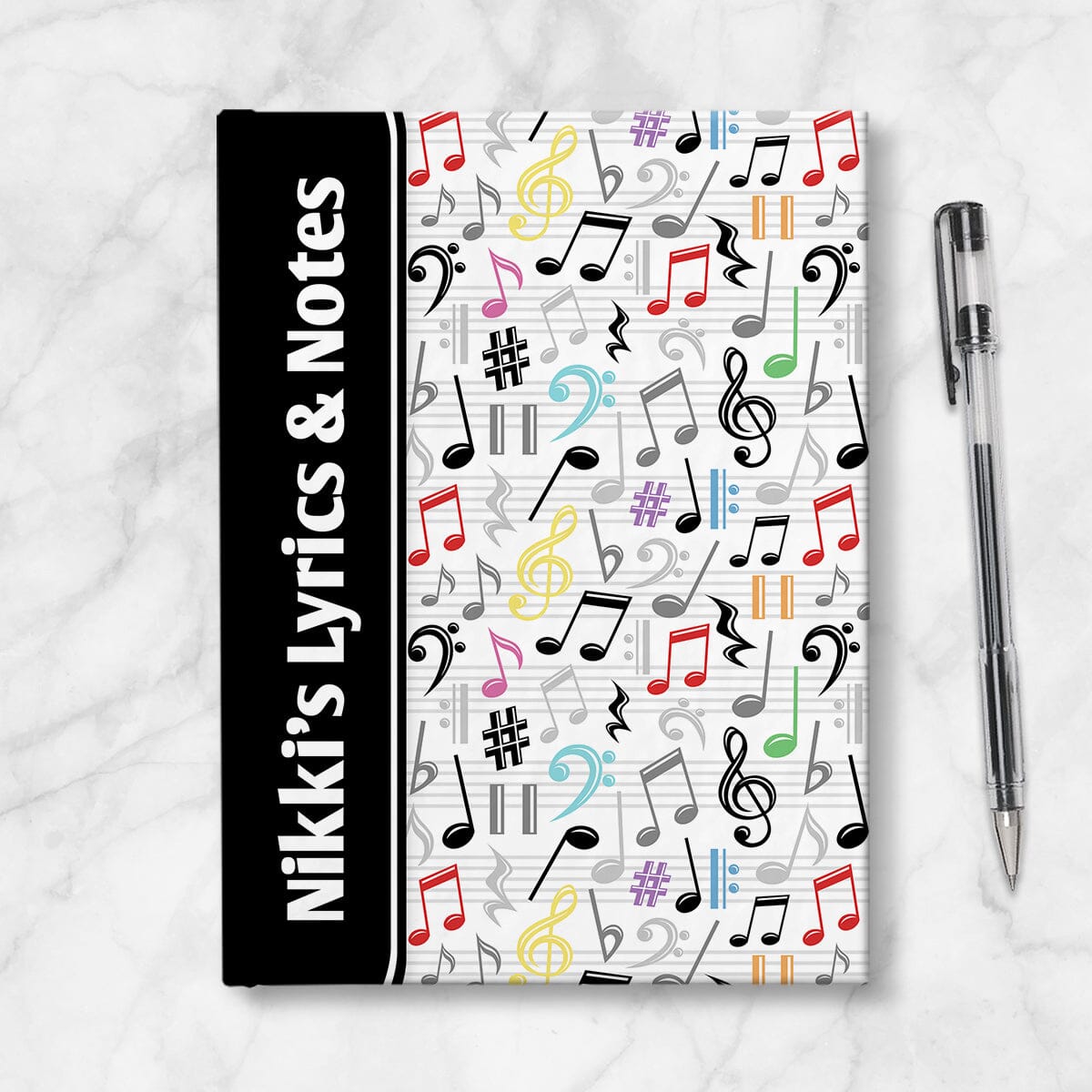 Personalized Colorful Music Notes Pattern Journal at Artistically Invited. A custom book designed with a black color block wrapping around the spine area over an energetic pattern of black, gray, and rainbow-inspired colorful music notes and symbols on the rest of the background. Your personalized name and text of your choice is custom printed sideways in white over the black color on the front near the spine. Image shows the book next to a pen.