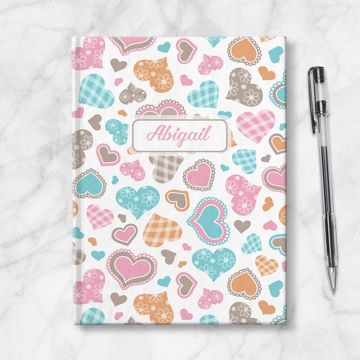 Personalized Cutesy Hearts Pattern Journal at Artistically Invited. Image shows book on countertop with a pen next to it.