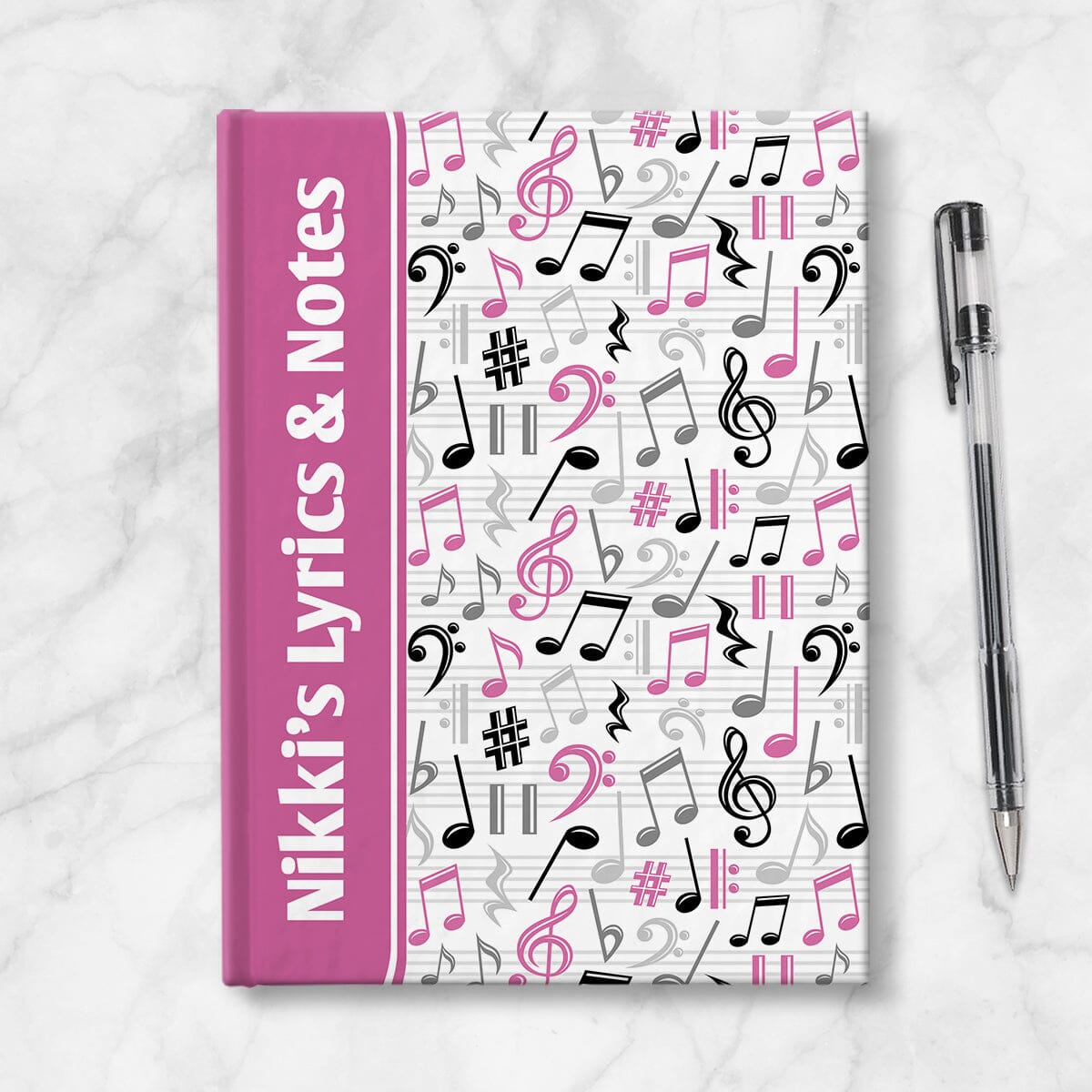 Personalized Pink Music Notes Pattern Journal at Artistically Invited. A custom book designed with a pink color wrapping around the spine area over an energetic pattern of pink, black, and gray music notes and symbols on the rest of the background. Your personalized name and text of your choice is custom printed sideways in white over the pink color on the front near the spine. Image shows the book next to a pen.