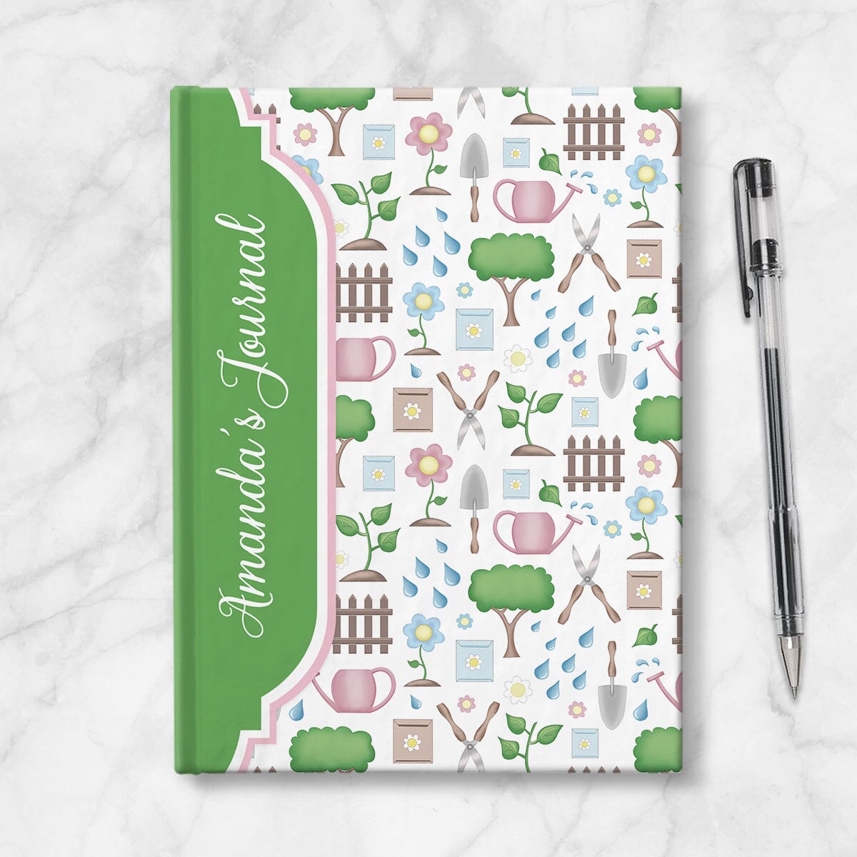 Personalized Spring Gardening Pattern Journal at Artistically Invited. A custom book designed with a pattern of gardening tools such as spades, watering cans, seed packets, shears, and more, and garden elements such as trees, plants, and flowers. Your personalized name is custom printed sideways in a white script font over a green frame area on the front side of the book that wraps around the spine. Image shows the book next to a pen.