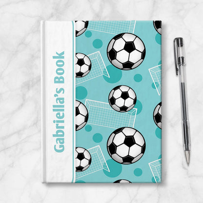 Personalized Teal Soccer Journal at Artistically Invited. Image shows the book on a countertop next to a pen.