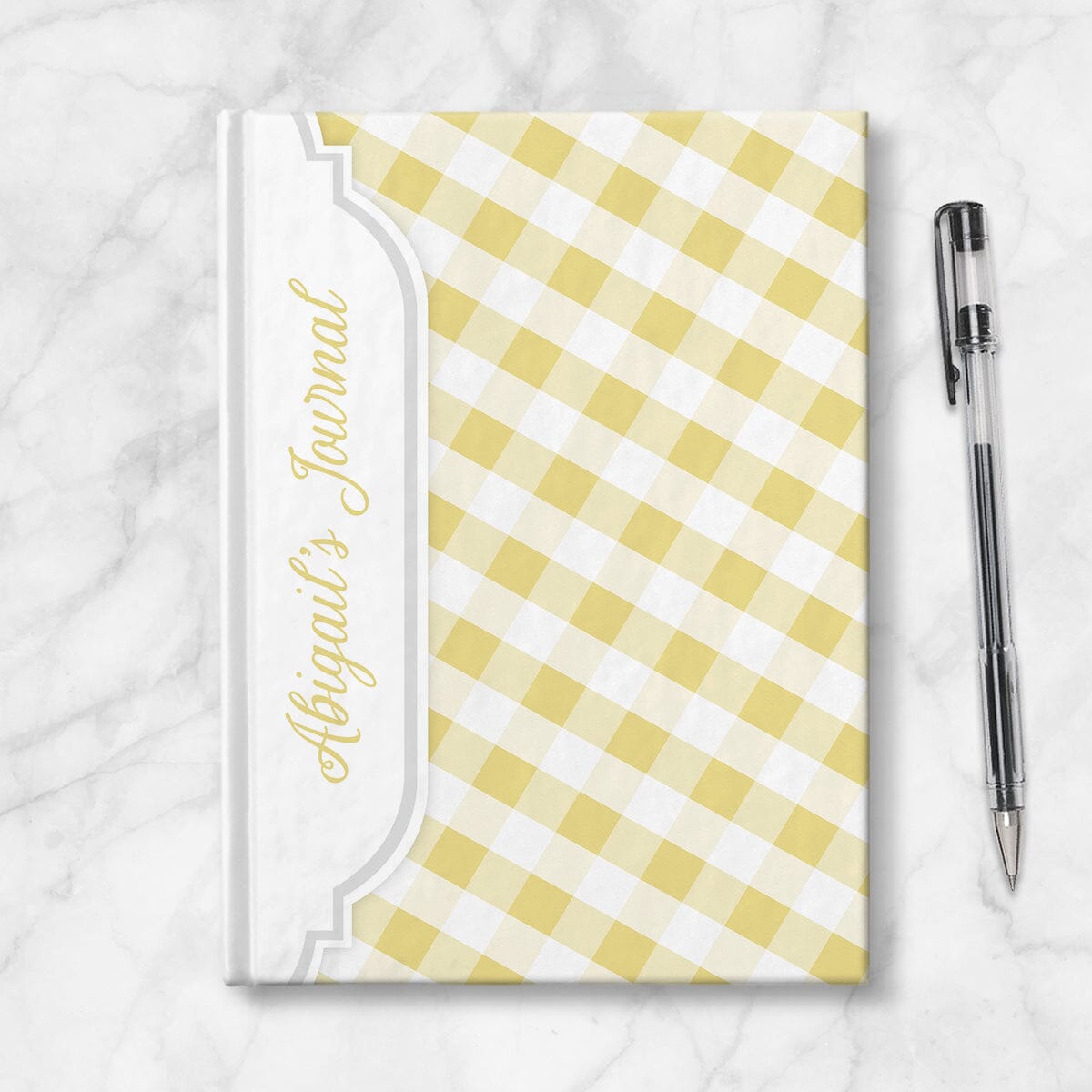 Personalized Yellow Gingham Journal at Artistically Invited. Image shows the book on a countertop next to a pen.