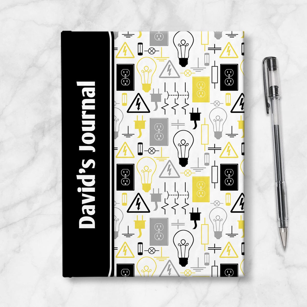 Personalized Yellow Electrical Pattern Journal at Artistically Invited. A custom book designed with a black color black wrapping over the spine area, over a yellow electrical pattern over the rest of the cover. This pattern has different electrical symbols and other images related to electricity in yellow, black, and gray. Your name is printed sideways in white over the black color block area on the front of the cover near the spine. Image shows the book next to a pen.