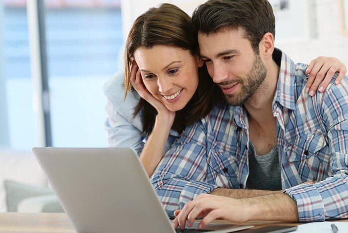 A couple viewing a laptop screen together.