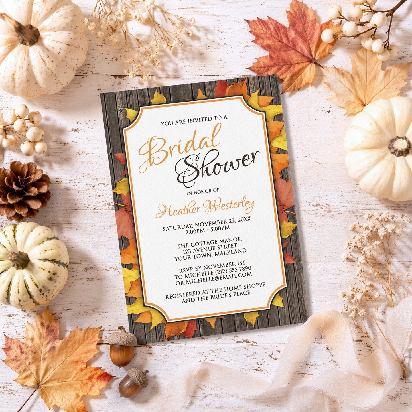Autumn Orange White Wood Bridal Shower Invitation shown on a rustic surface with fall leaves and autumn decor.