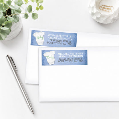 Baby Bodysuit on Blue Address Labels, shown on white envelopes, on a white surface with a plant and a pen.