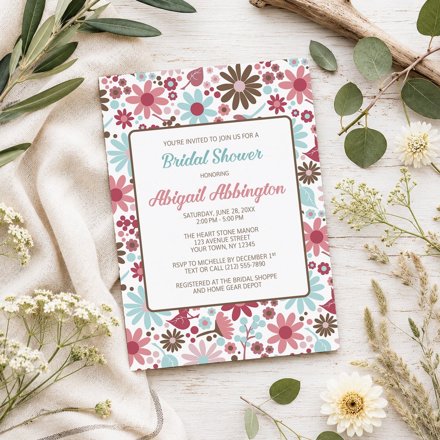 Berry Blue Summer Flowers Bridal Shower Invitation shown on a light wooden surface with spring and summer plants.