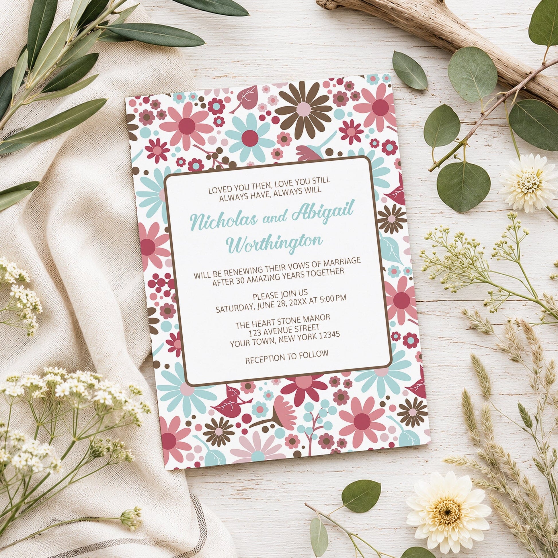 Berry Blue Summer Flowers Vow Renewal Invitation shown on a light wooden surface with spring and summer plants.