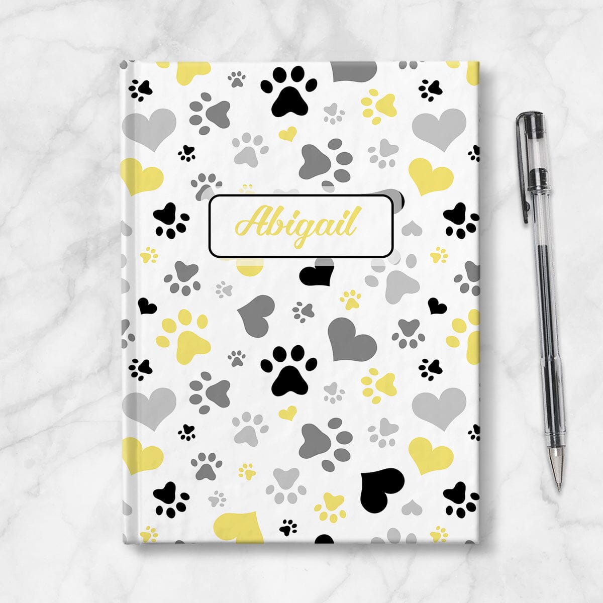Personalized Black Yellow Hearts and Paw Prints Journal at Artistically Invited. Image shows the book on a countertop next to a pen.