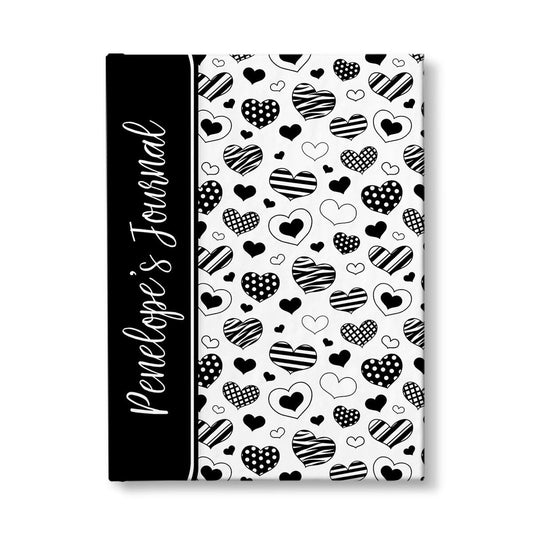 Personalized Black Heart Doodles Journal at Artistically Invited. A custom book featuring a pattern of hand-drawn hearts with different patterns and styles over a white background. Your personalized name is printed in a white handwriting font sideways on the front of the book over a black color block that wraps around the spine area.
