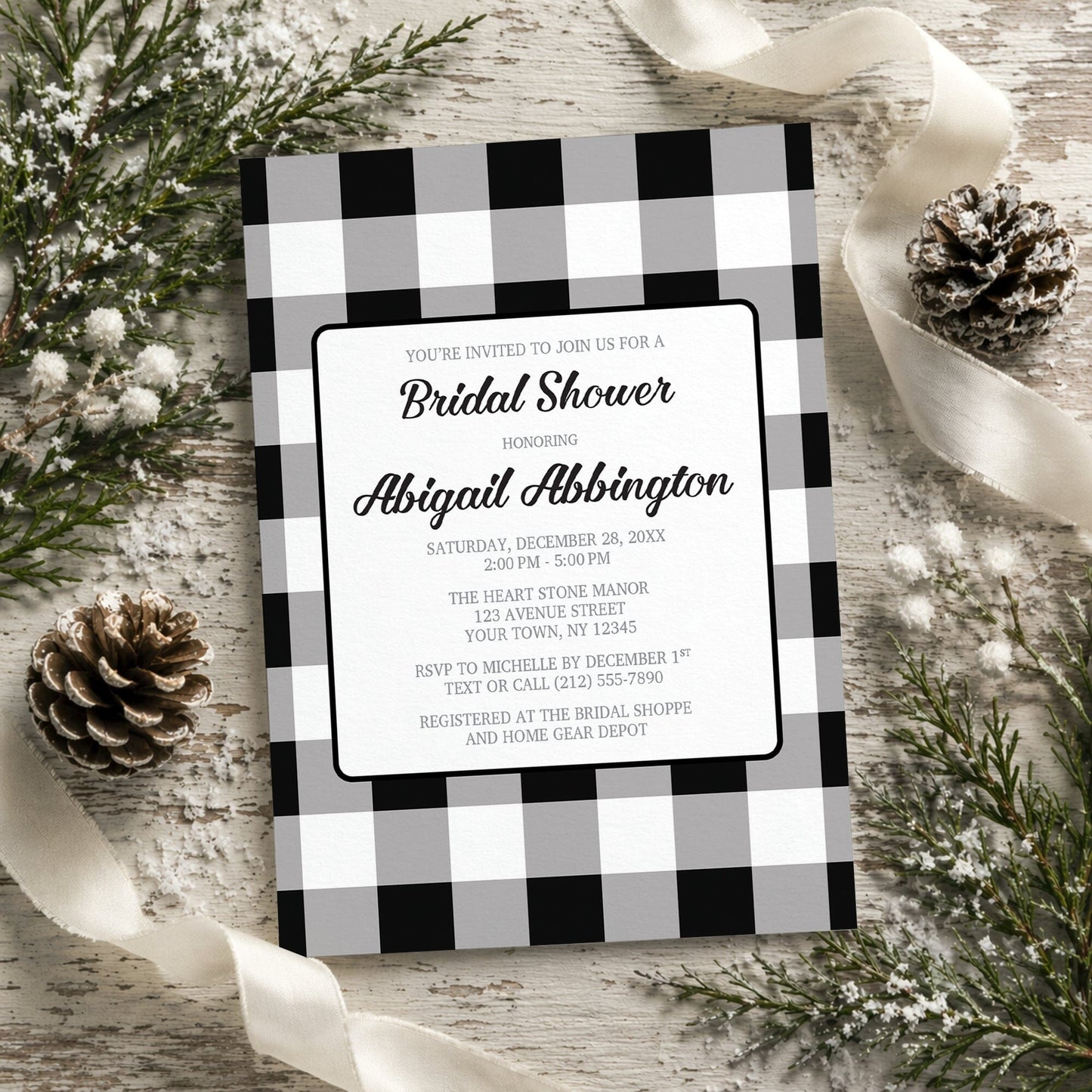 Black and White Buffalo Plaid Bridal Shower Invitation with black and white checkered border on a rustic background with pine cones and ribbons.