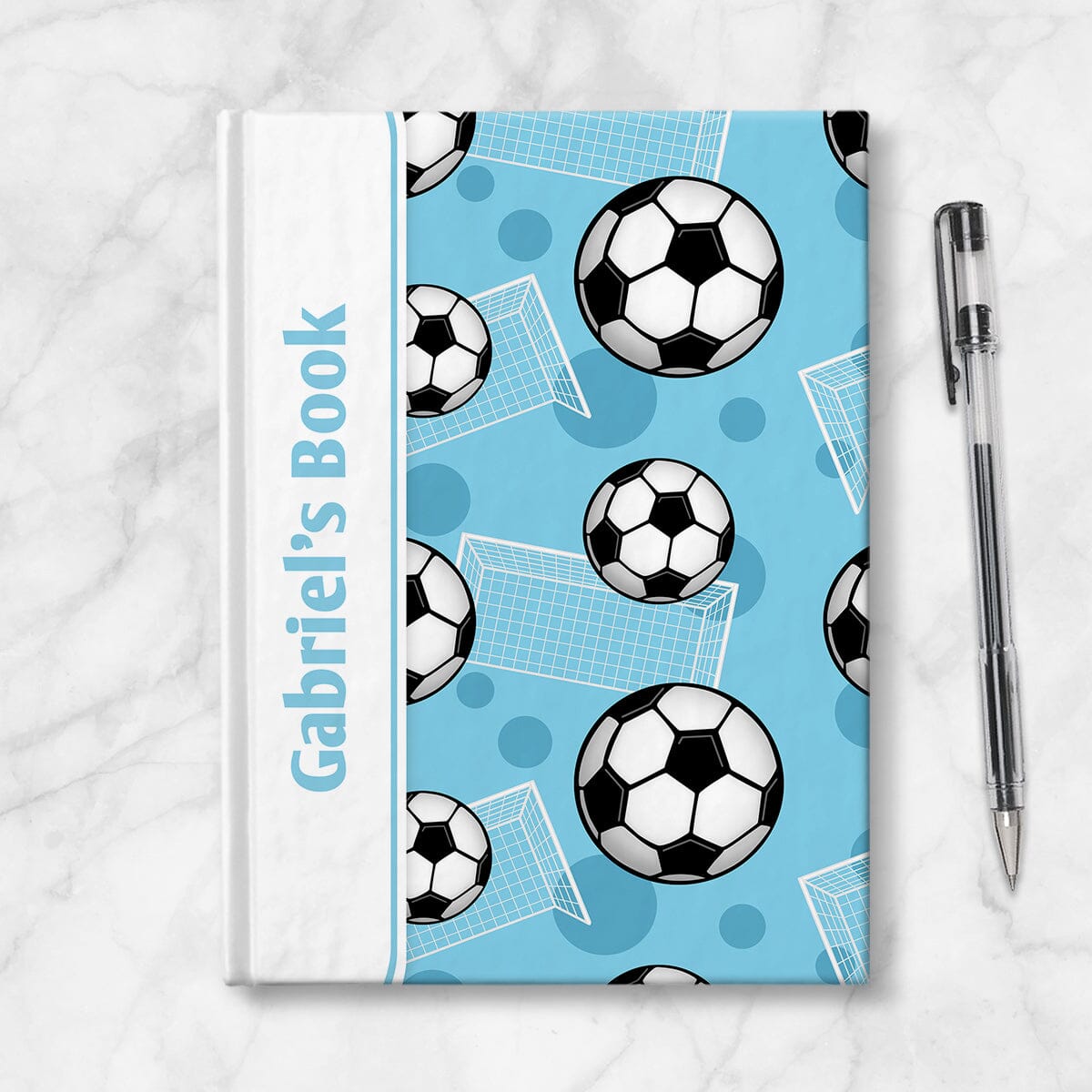 Personalized Blue Soccer Journal at Artistically Invited. Image shows the book on a countertop next to a pen.