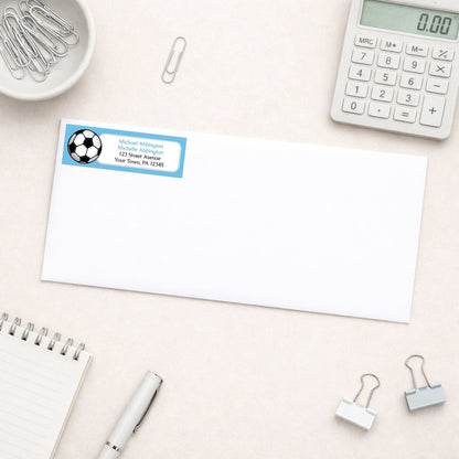 Blue Soccer Ball Return Address Label shown on a white envelope with everyday office supplies