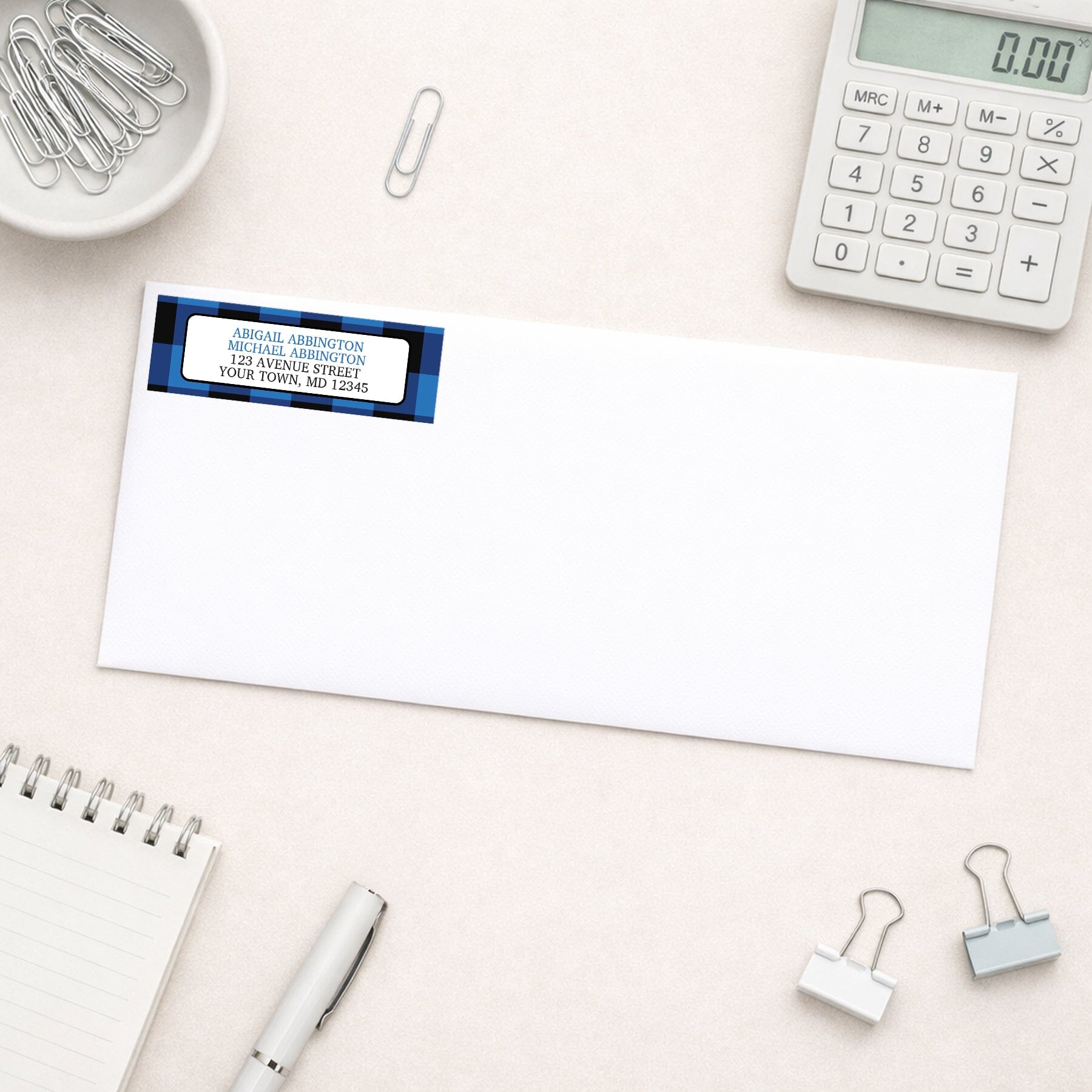Blue and Black Buffalo Plaid Address Label shown on a white envelope with everyday office supplies