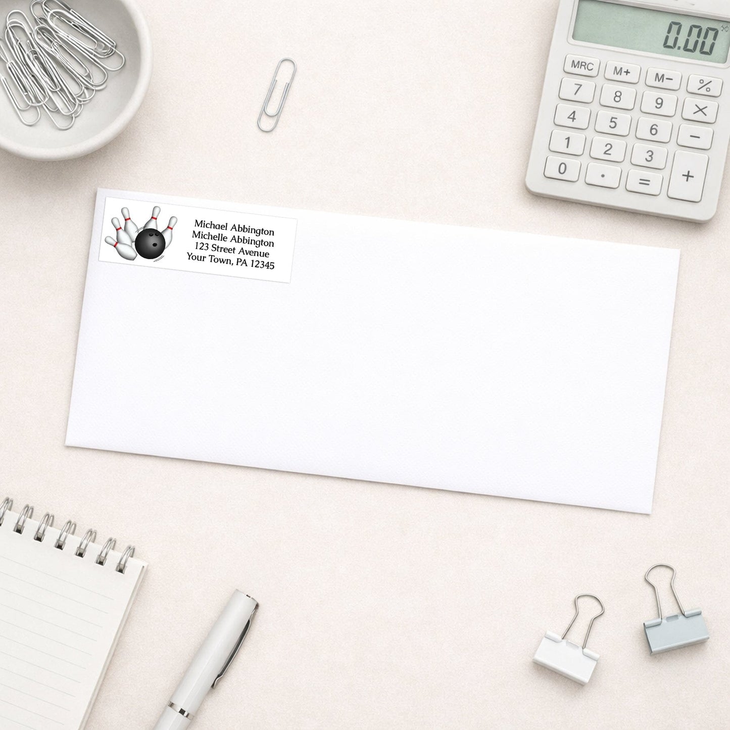 Bowling Ball and Pins Address Label shown on a white envelope with everyday office supplies