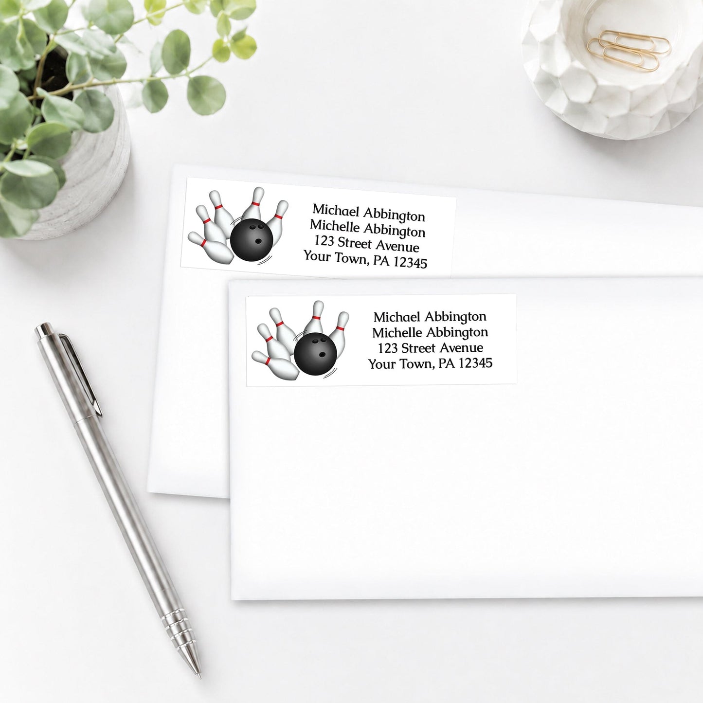 Address labels with bowling design, shown on white envelopes, on a white surface with a pen and plant.