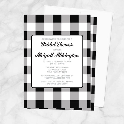 Bridal shower invitation with black and white checkered border, with a white envelope, on a marble background