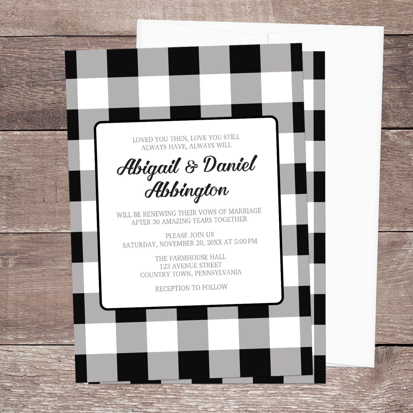 Black and White Buffalo Plaid Vow Renewal Invitation with black and white checkered border shown on a wooden surface with a white envelope.