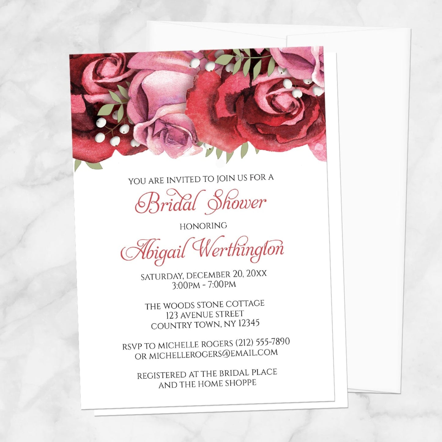 Bridal shower invitation with burgundy-red and pink roses along the top, displayed with a white envelope on a marble surface