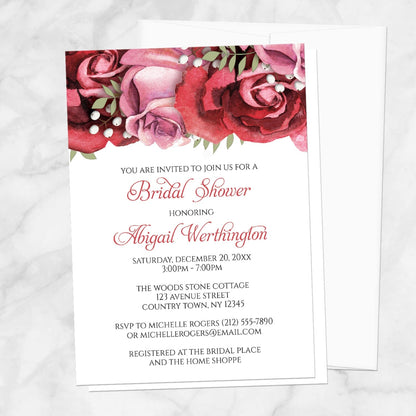 Bridal shower invitation with burgundy-red and pink roses along the top, displayed with a white envelope on a marble surface