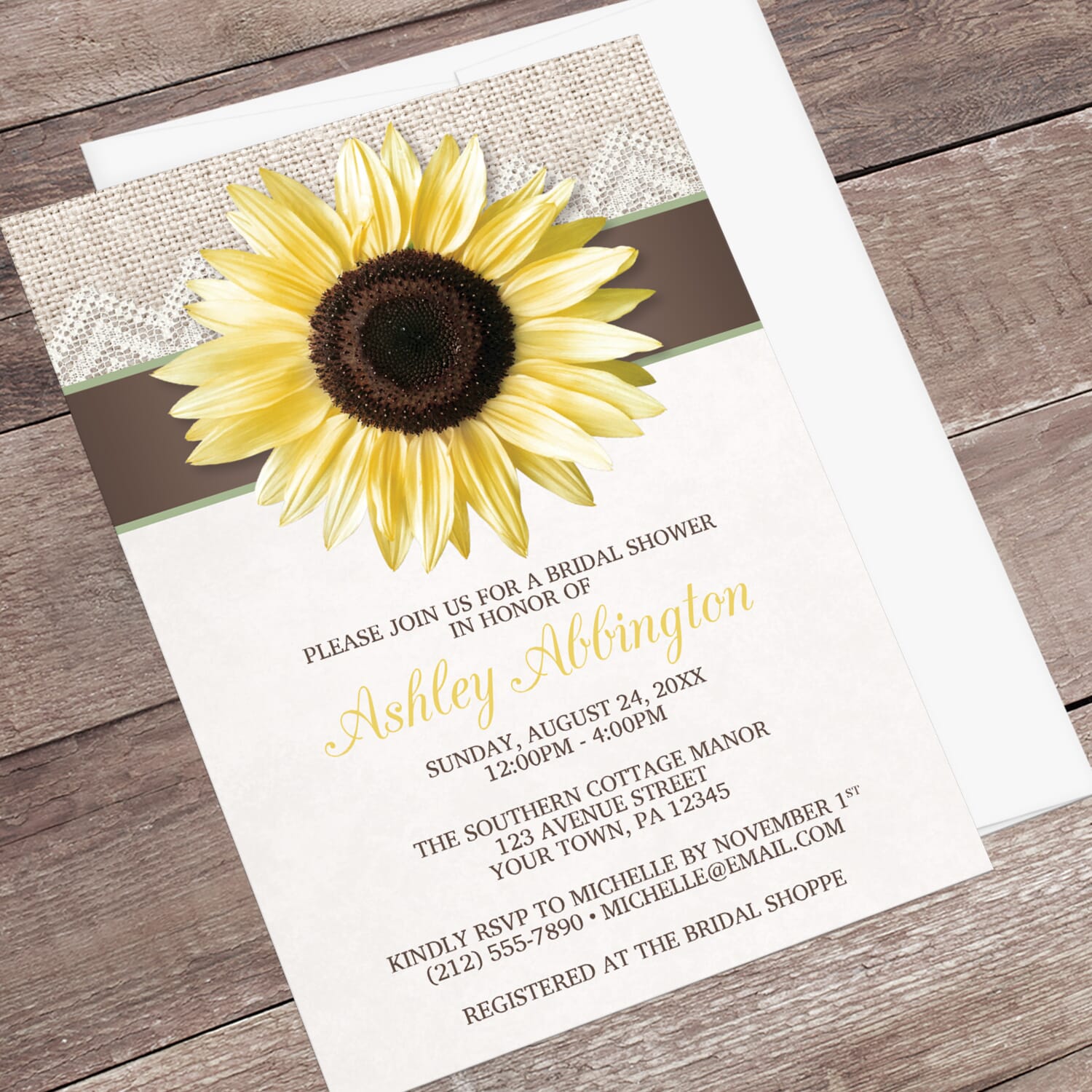 Rustic bridal shower invitation with a large yellow sunflower, burlap and lace, with brown and beige, displayed at an angle with a white envelope on a wood surface