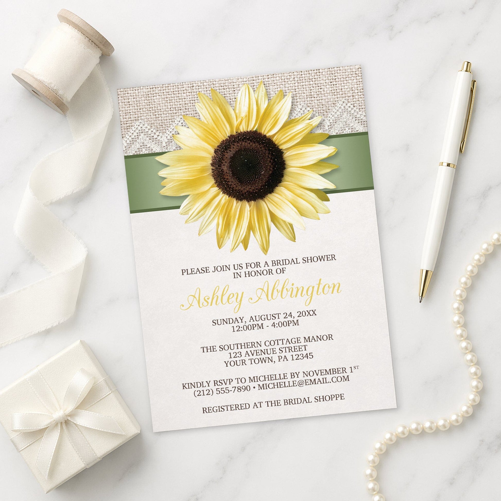 Burlap and Lace Sage Sunflower Bridal Shower Invitation on a marble surface with a gift box, pen, and pearls.