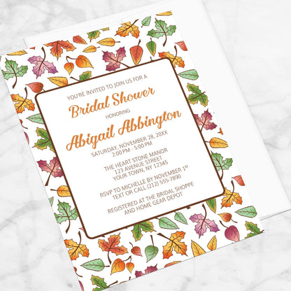 Changing Leaves Fall Bridal Shower Invitation shown at an angle on a marble surface.