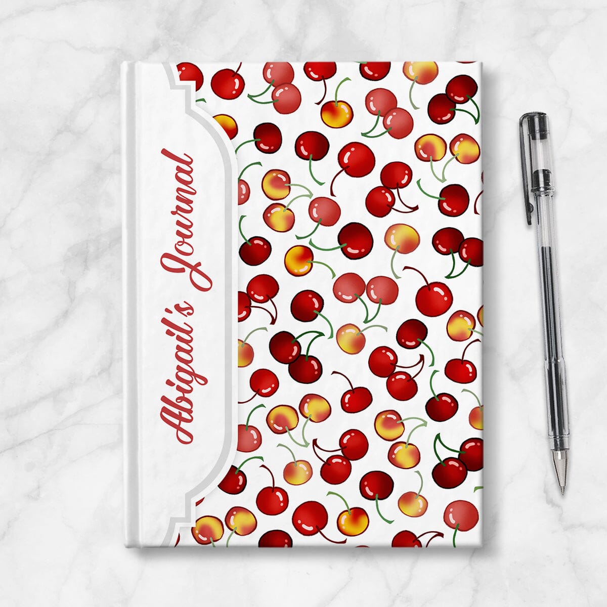 Personalized Cherries Journal at Artistically Invited. Image shows the book on a countertop next to a pen.