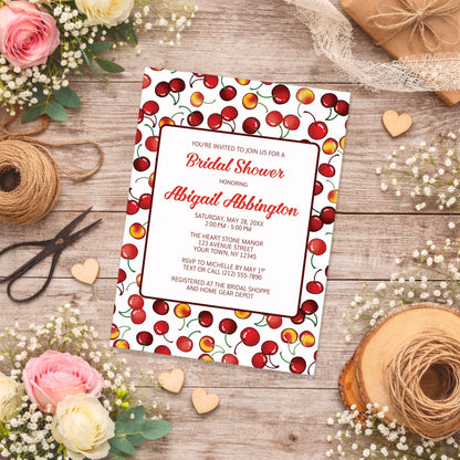 Cherries Bridal Shower Invitation on a wooden surface with flowers and twine.