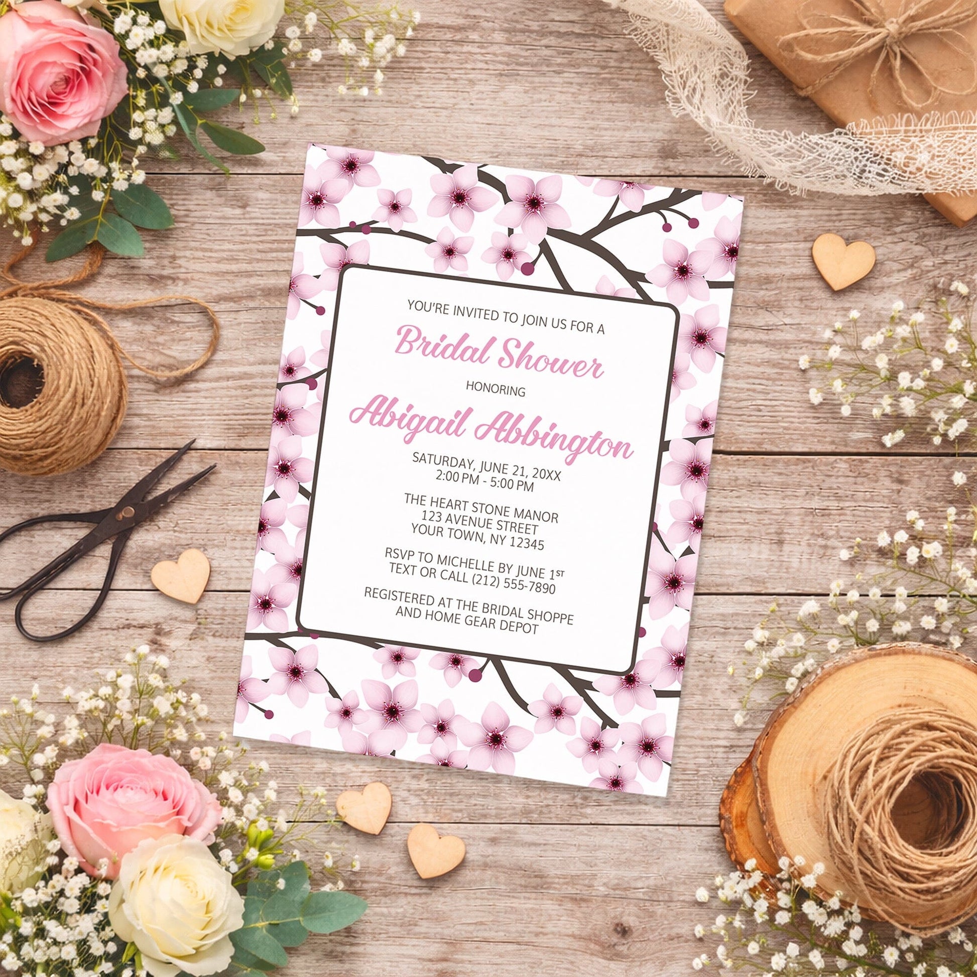 Cherry Blossom Bridal Shower Invitation on a wooden surface with flowers and twine.