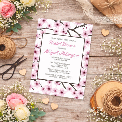 Cherry Blossom Bridal Shower Invitation on a wooden surface with flowers and twine.