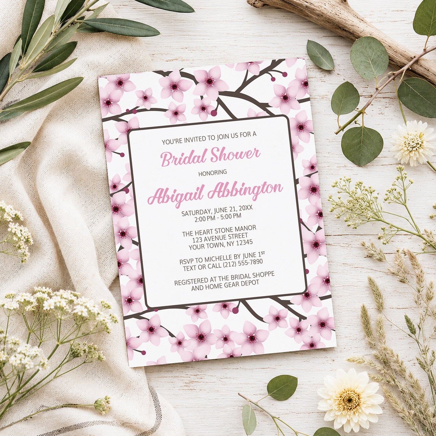Cherry Blossom Bridal Shower Invitation shown on a light wooden surface with spring and summer plants.
