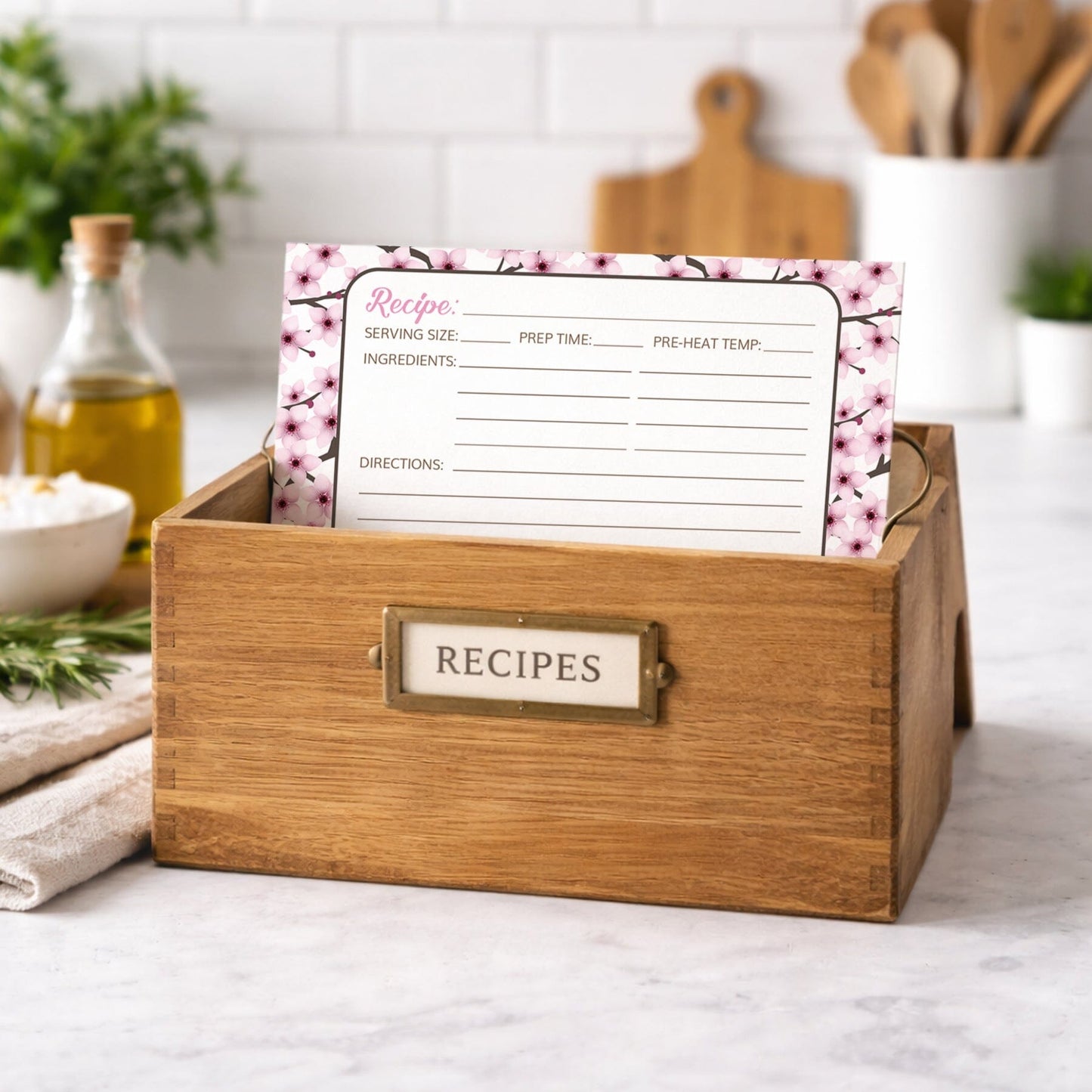 Wooden recipe box with a Cherry Blossom Recipe Card on a kitchen counter.