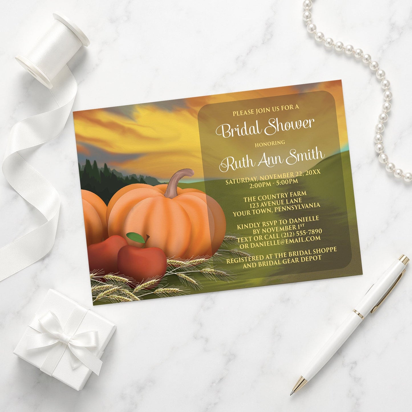 Country Autumn Harvest Bridal Shower Invitation with pumpkins and apples shown on a marble surface with a white gift box, pen, ribbon, and pearls.