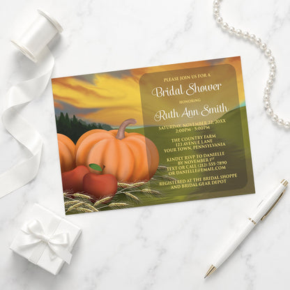 Country Autumn Harvest Bridal Shower Invitation with pumpkins and apples shown on a marble surface with a white gift box, pen, ribbon, and pearls.