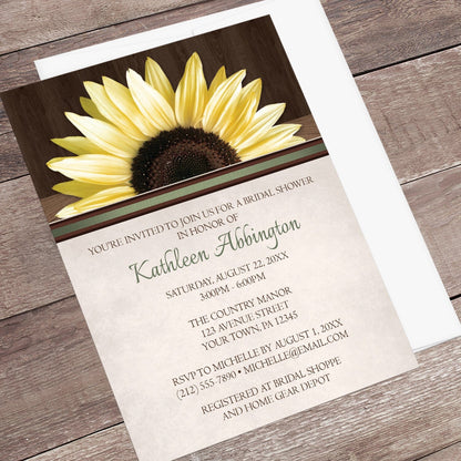Country Sunflower Over Wood Rustic Bridal Shower Invitation shown at an angle on a wooden surface with a white envelope.