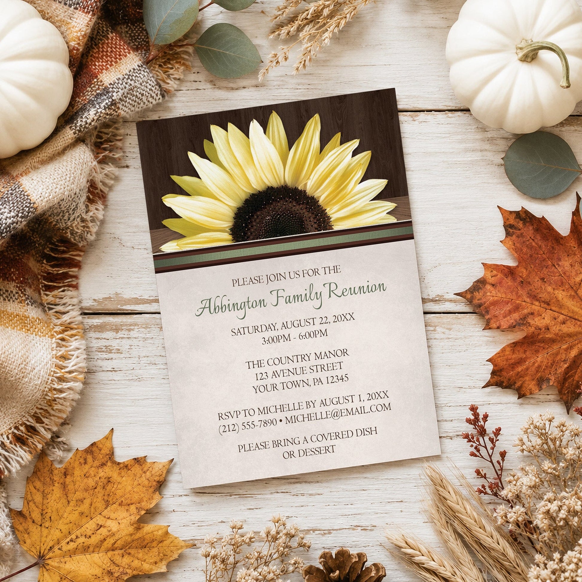 Country Sunflower Over Wood Rustic Family Reunion Invitation shown on a wooden surface with fall leaves and autumn decor.