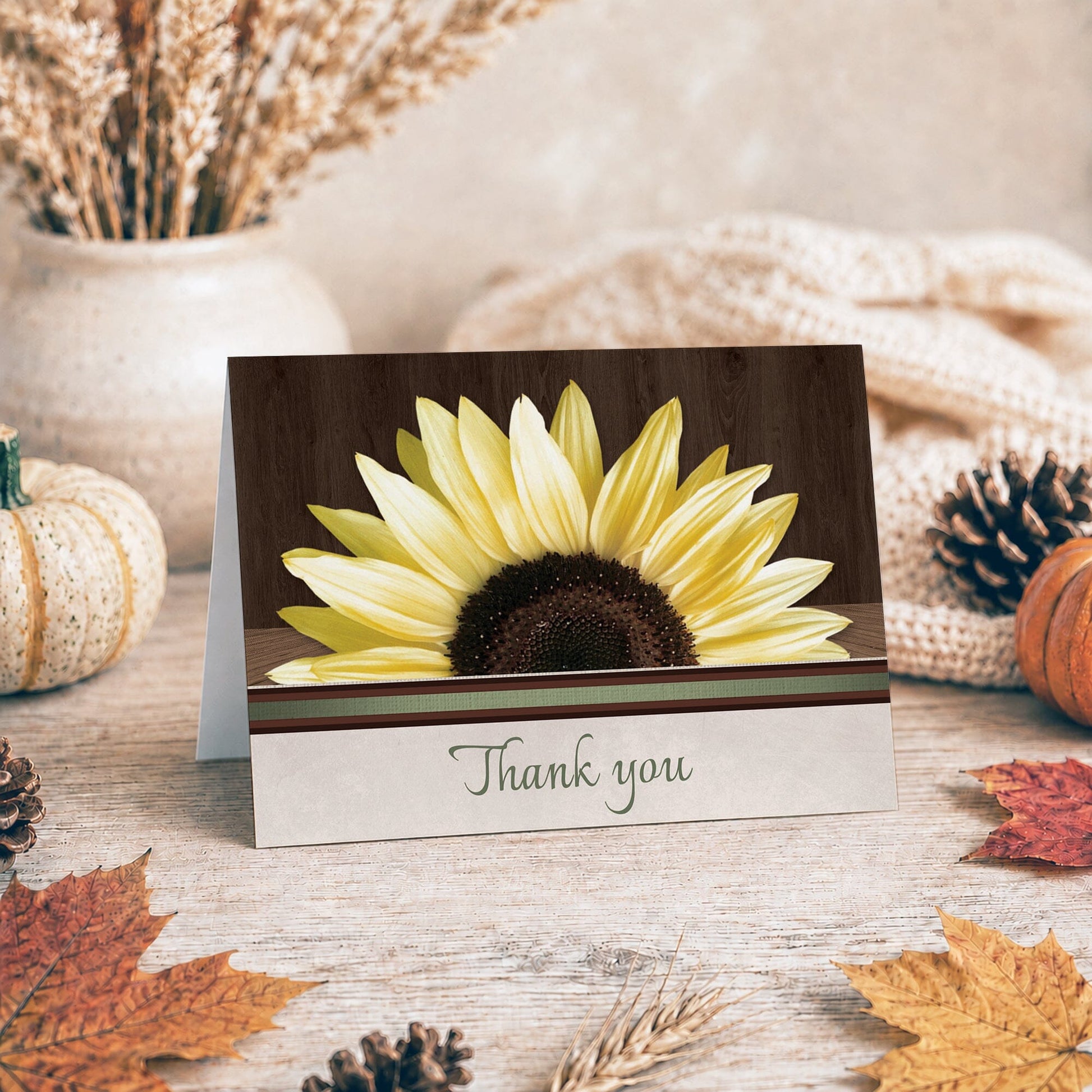 Country Sunflower Over Wood Rustic Thank You Card shown on a tabletop with fall leaves and autumn decor.