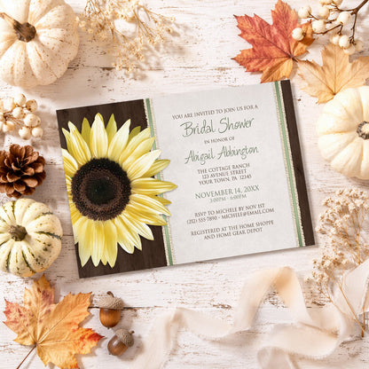 Country Sunflower Wood Brown Green Bridal Shower Invitation on a wooden surface with fall decorations.