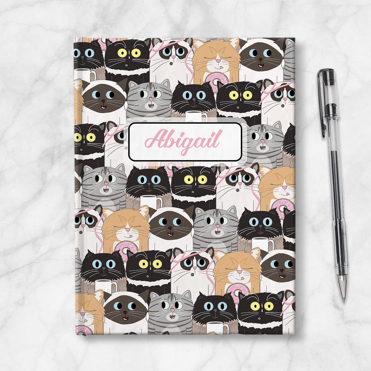 Personalized Cute Cat Stack Pattern Journal at Artistically Invited. Front side of journal shown on table next to a pen.