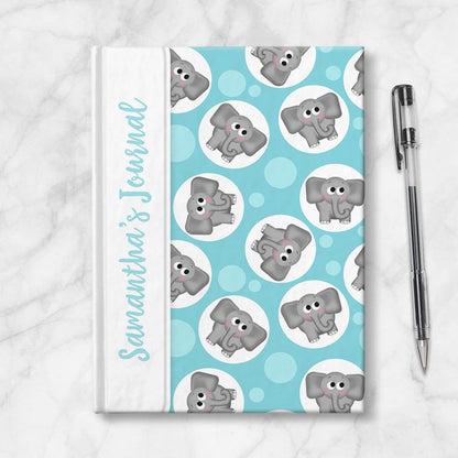 Personalized Cute Turquoise Elephant Journal at Artistically Invited. Image shows the book on a countertop next to a pen.