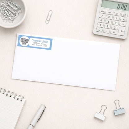 Cute Elephant Blue Address Label shown on a white envelope with everyday office supplies