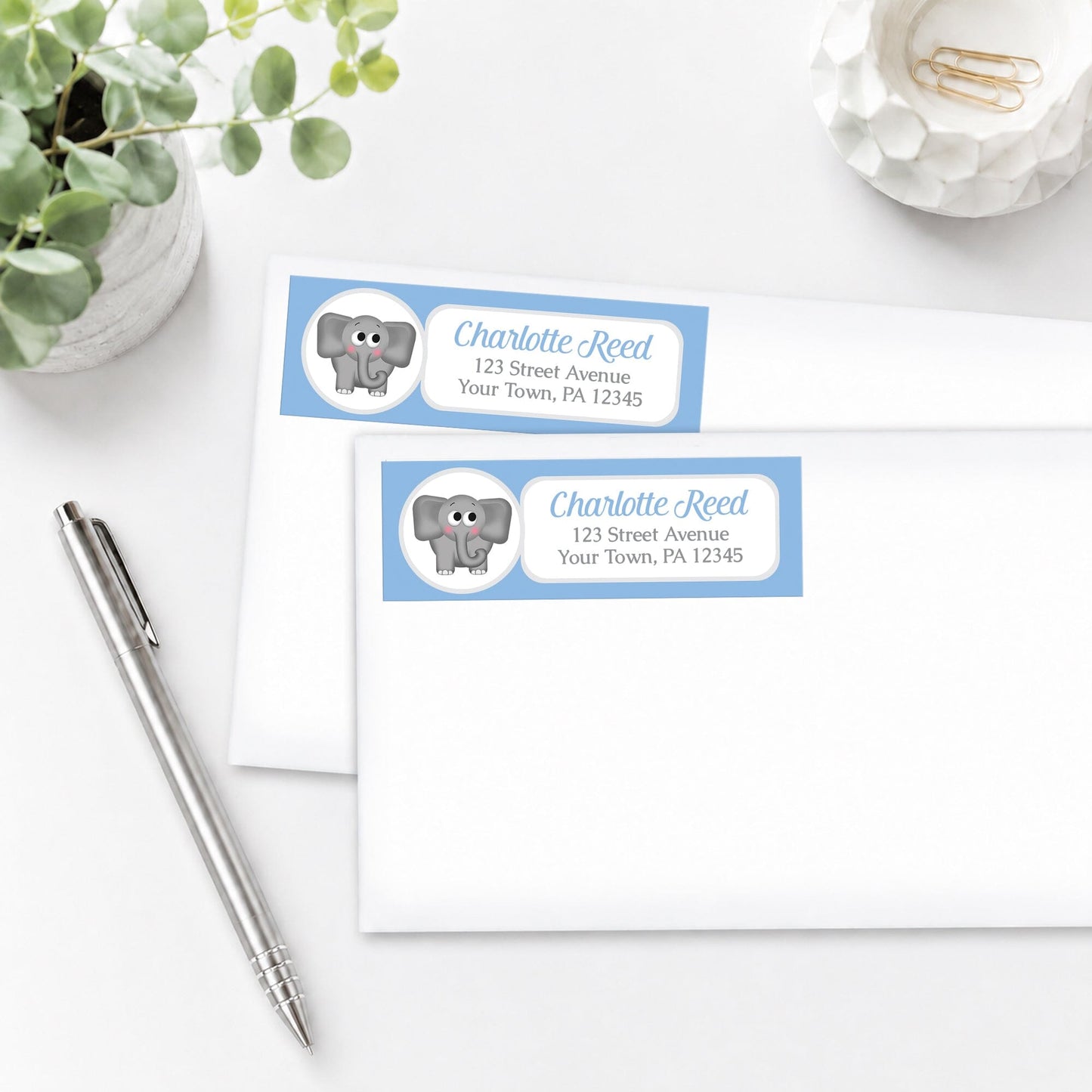 Cute Elephant Blue Address Labels, shown on white envelopes, on a white surface with a pen and plant.