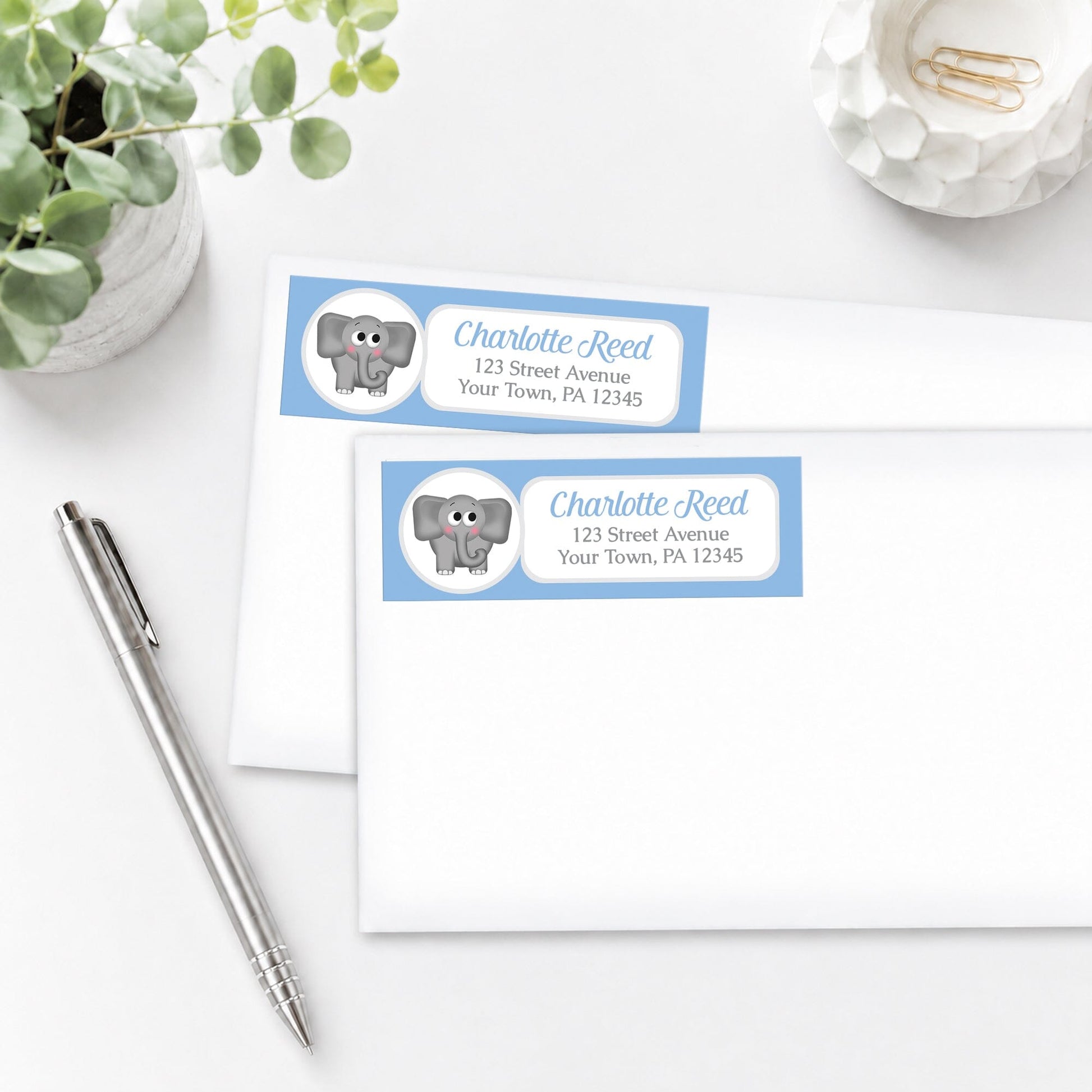 Cute Elephant Blue Address Labels, shown on white envelopes, on a white surface with a pen and plant.