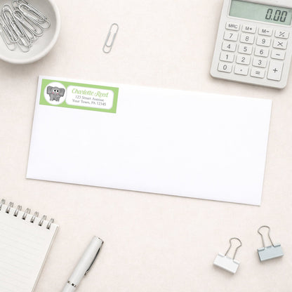 Cute Elephant Green Address Label shown on a white envelope with everyday office supplies