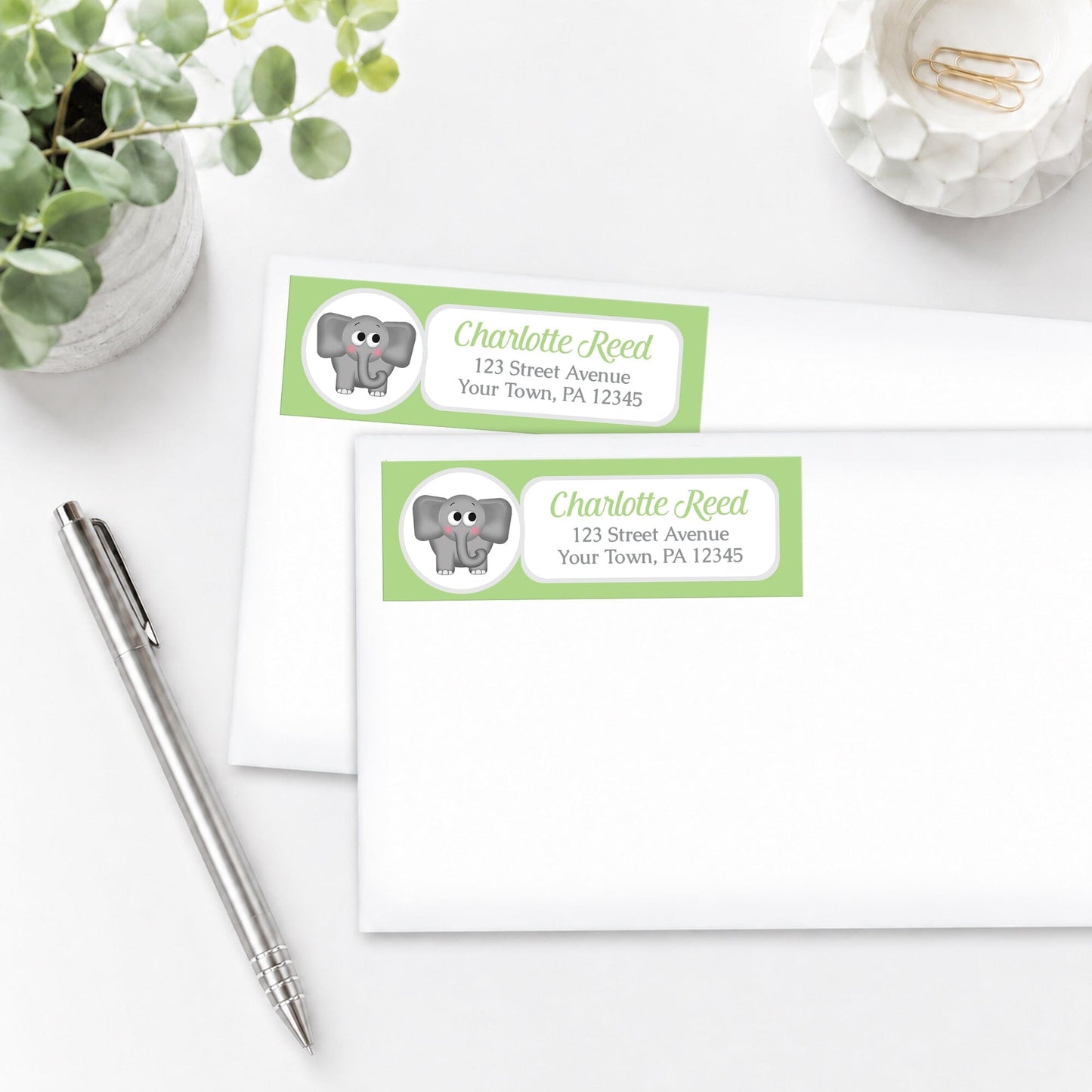 Cute Elephant Green Address Labels, shown on white envelopes, on a white surface with a pen and plant.
