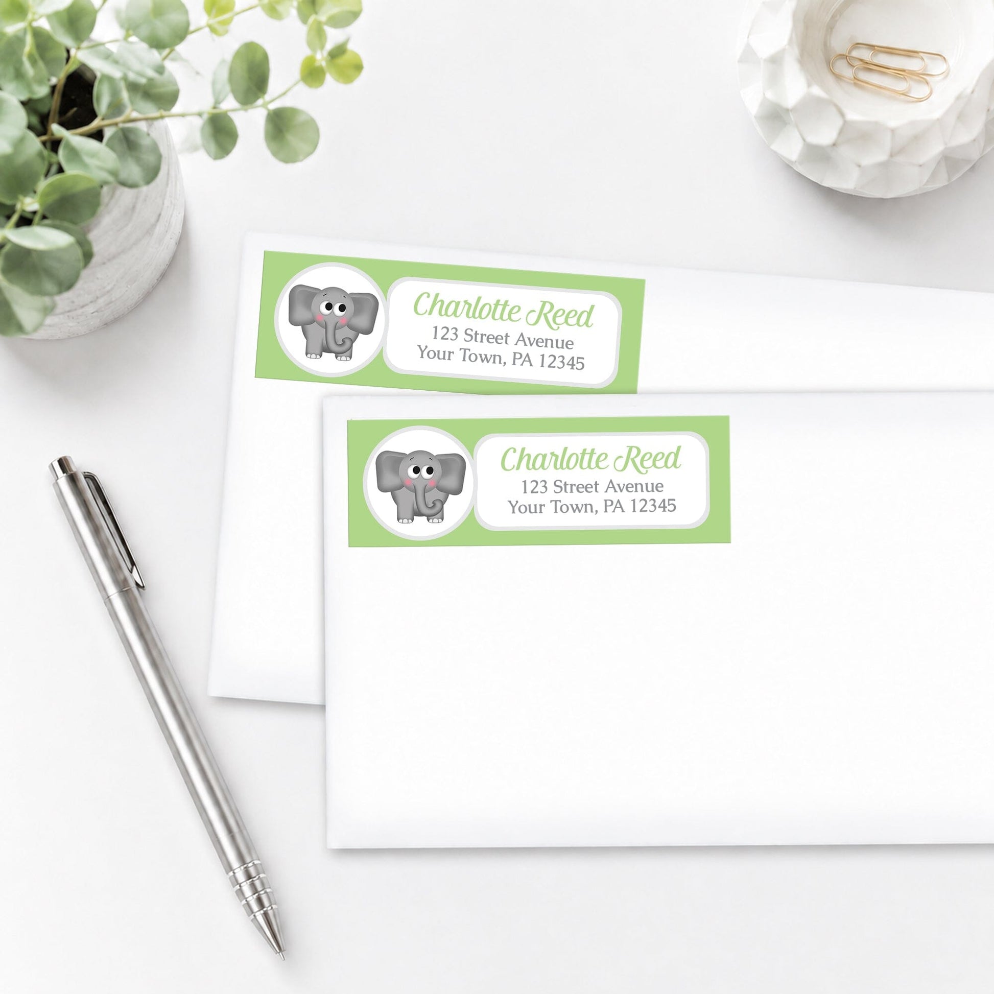 Cute Elephant Green Address Labels, shown on white envelopes, on a white surface with a pen and plant.