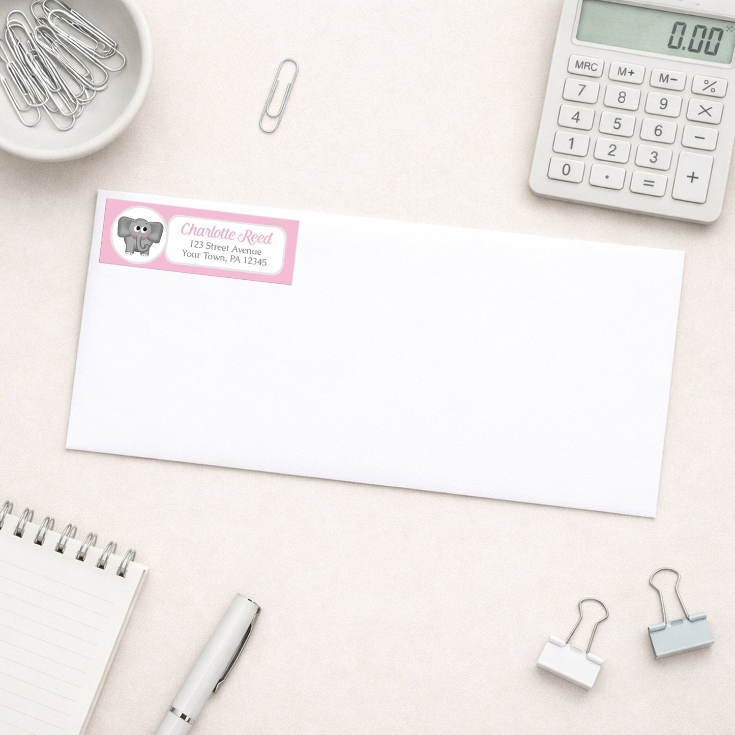 Cute Elephant Pink Address Label shown on a white envelope with everyday office supplies