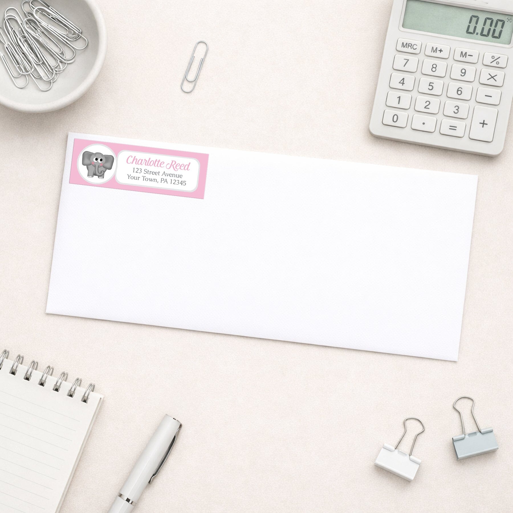 Cute Elephant Pink Address Label shown on a white envelope with everyday office supplies